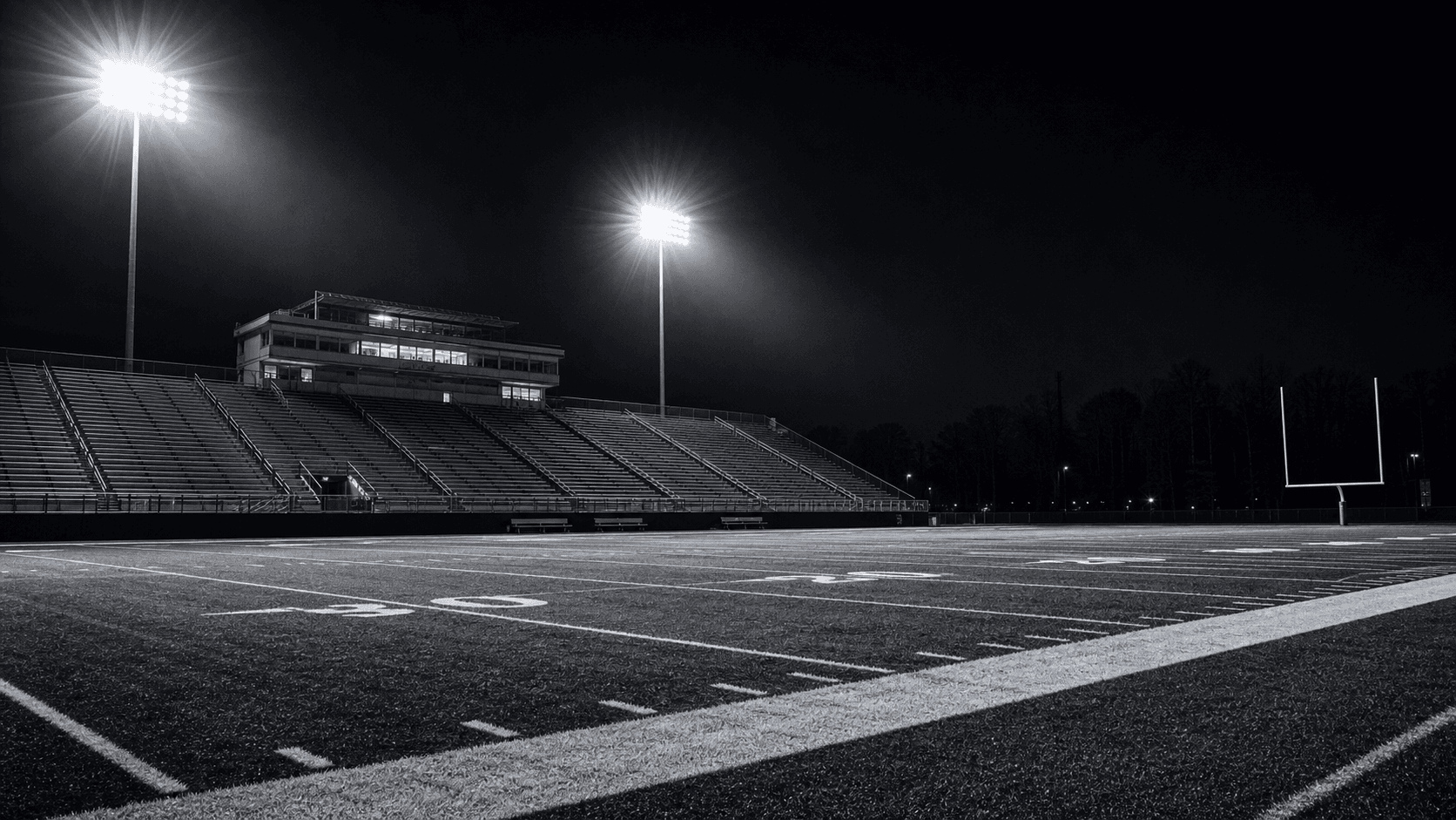 Generic high school football stadium under Friday night lights